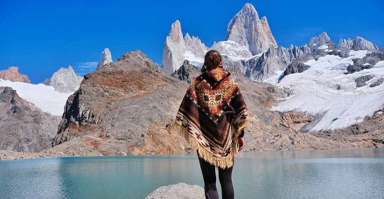 Jeune randonneuse en poncho devant un lac dans les Andes