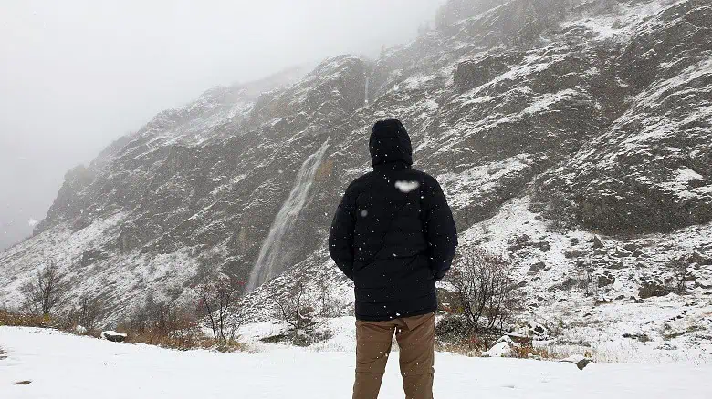 Doudoune en duvet Columbia devant une cascade sous la neige