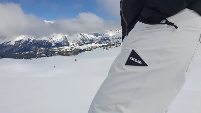 Gros plan sur le logo Capelin Crew du pantalon Torque, lors des tests en montagne