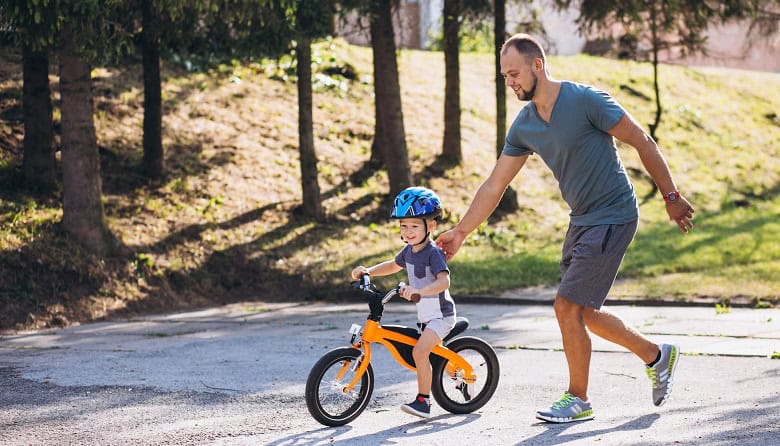 Jeune enfant apprenant à faire du vélo avec son papa