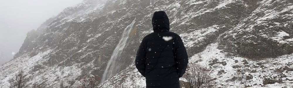 Doudoune en duvet Columbia devant une cascade sous la neige