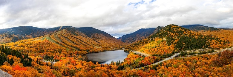 vue sur un lac de montagne au milieu des forets aux couleurs de l'automne
