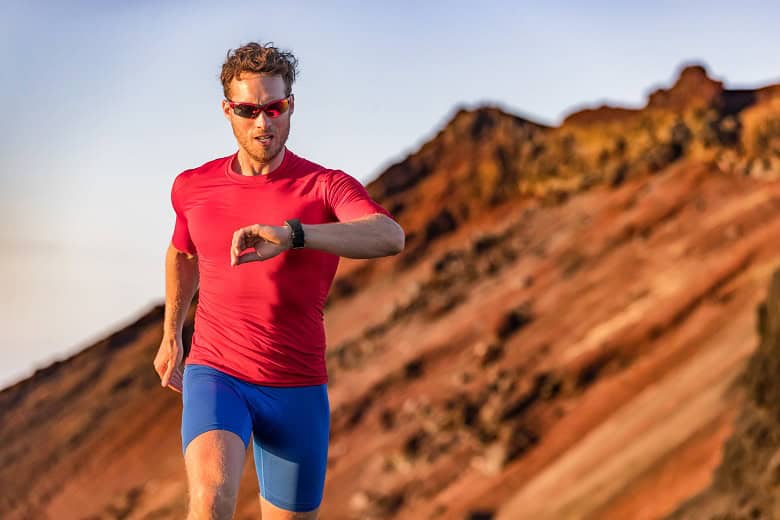 traileur en tshirt rouge courant avec des lunettes de soleil pour regarder sa montre