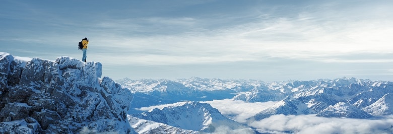 homme pratiquant la randonnée en hiver au bord d'une falaise pleine de neige