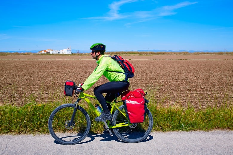 bikepacker avec plusieurs sacoches de vélo sur un chemin de plaine