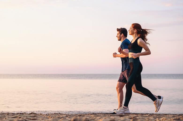 jeune couple sportif sourant sur une plage