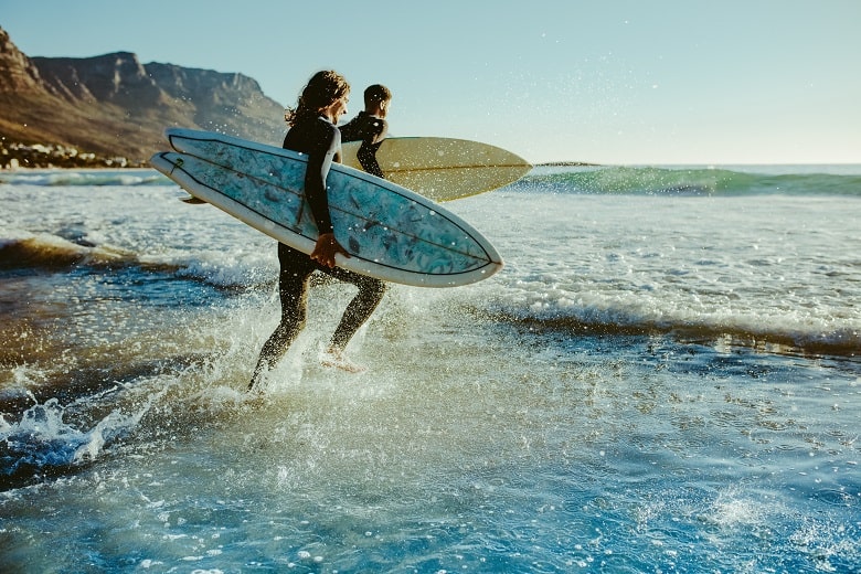 2 surfeurs se mettant à l'eau