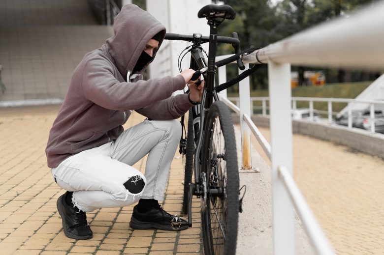 voleur masqué decoupant l'antivol d'un vélo